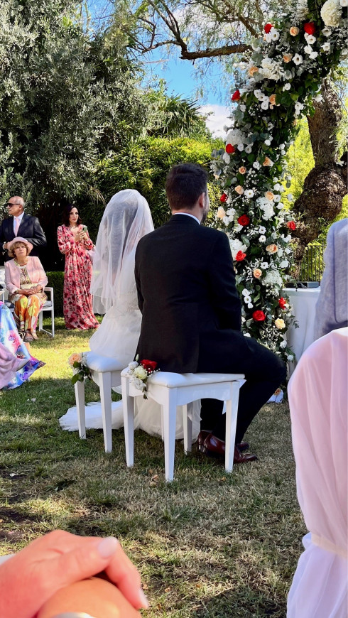 Filly and Jay sitting in front of the wedding arch at the ceremony.