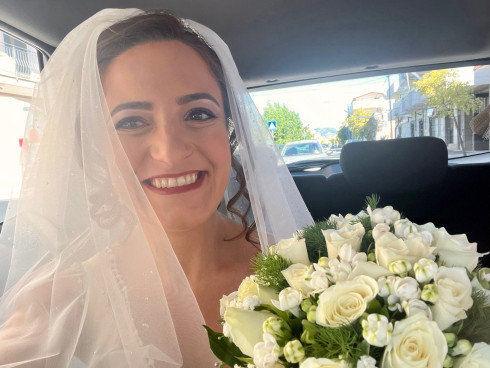Filly in the taxi on the way to the venue, holding flowers and smiling.