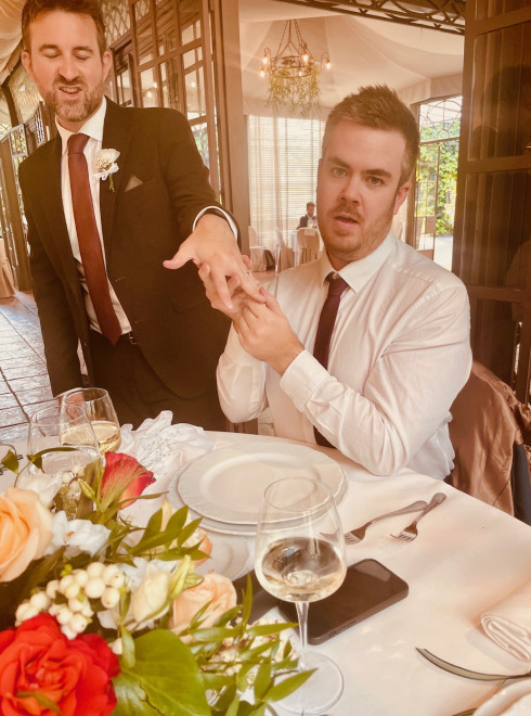 Jay posing with his ring in front of Lewis at the table.