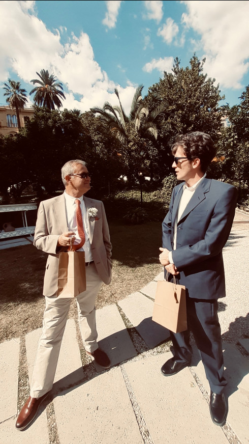 Dad and Giulio holding gift bags chatting in the driveway.