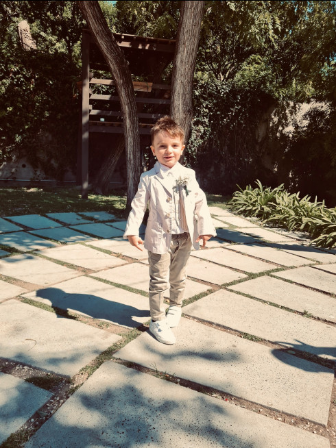 Sergio posing for the camera stood in the garden with a treehouse behind him.