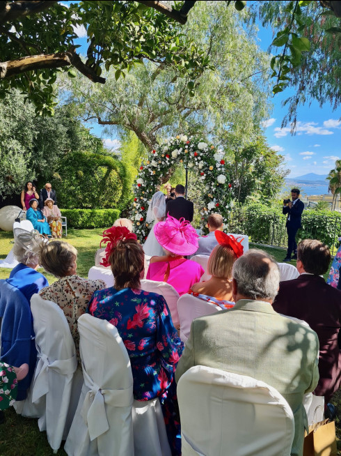 View of the guests sat down with Jay and Filly under the wedding arch.