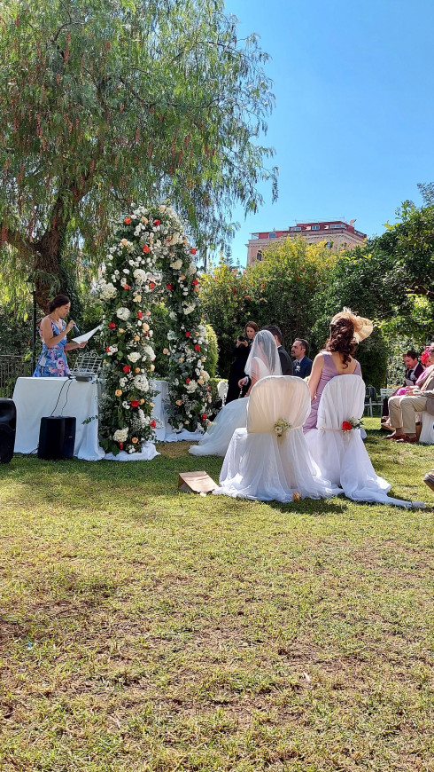 Daniella making her speech behind the flower arch, in front of Jay and Filly.