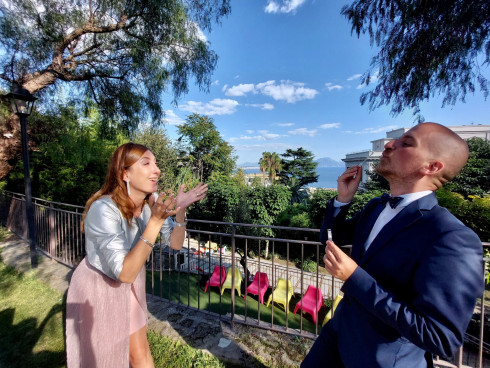 Vivienna and Marco blow bubbles in the garden, with the sea and mount Versuvius in the far distance.