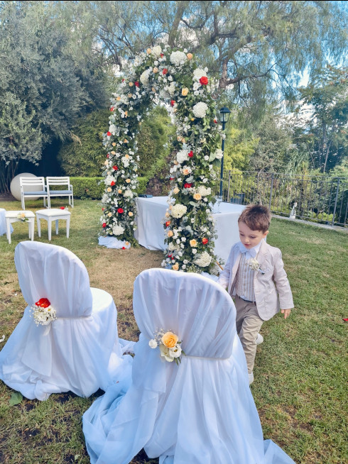 Sergio, a small child, in front of the wedding arch after everyone has left with empty seats.