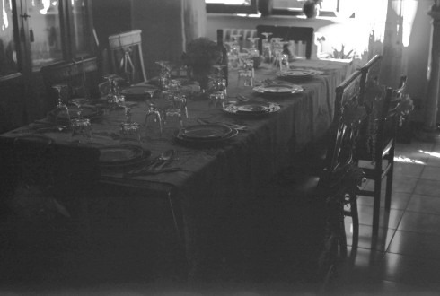 Black and white photo of the dining room set up with fancy plates and glasses.