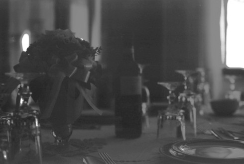 Black and white photo of the dining room, close up of the flowers and wine.